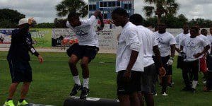 Coach Bryan Ingrande demonstrates a drill with a group of kids at the Youth Football Combine, Bill Spoone Stadium, June 1, 2013. (Photo: WONO)